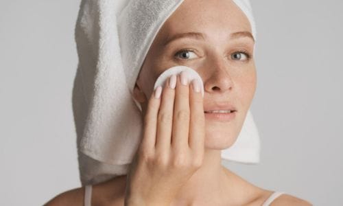 young-beautiful-woman-with-towel-on-head-cleaned-face-with-cotton-sponge